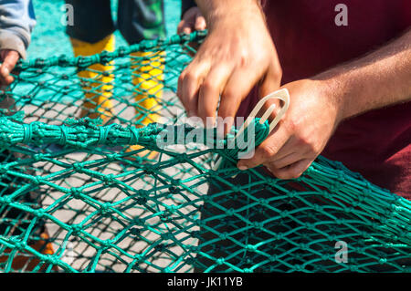 Fishermans mani riparazione riassettavano le reti nel porto di Killybegs County Donegal Irlanda Foto Stock