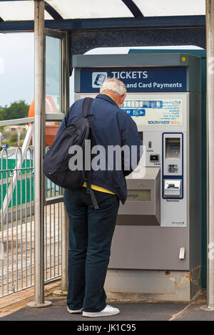 L uomo come ottenere i biglietti del treno dal ticket machine a Lymington, Hampshire nel luglio Foto Stock