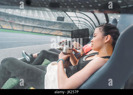 Stanco di giovani donne fitness abbigliamento sportivo in riposo in sedi stadium Foto Stock