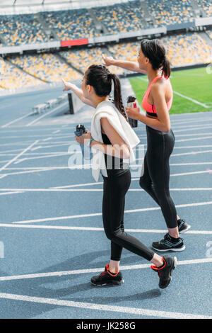 Stanco di giovani sportivi con bottiglie di acqua a camminare sulla via di corsa stadium Foto Stock