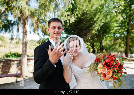 Felice sposa e lo sposo che mostra le loro dita ad anello con gli anelli di nozze su di essi. Foto Stock