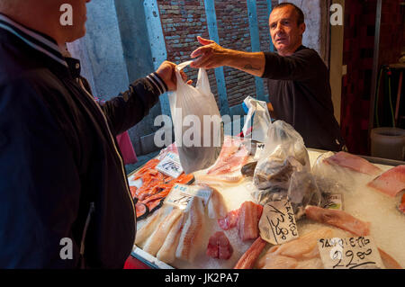 L'uomo l'acquisto di pesce in una fase di stallo in vendita al mercato di Rialto di Venezia Italia Foto Stock