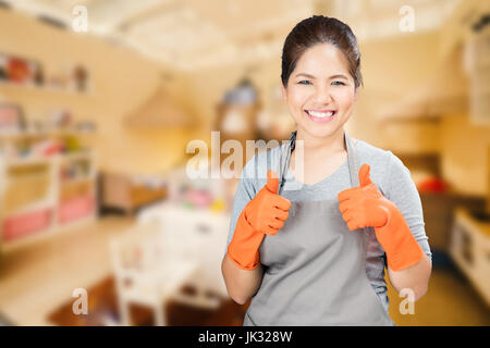 Asian casalinga indossando guanti di gomma pollice in alto Foto Stock