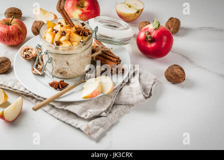 Sano cibo vegan. Dietetici di prima colazione o uno spuntino. La torta di mele per tutta la notte di avena, di mele, yogurt, cannella, spezie, noci. In un bicchiere, su un bianco marbl Foto Stock