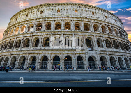 Il Colosseo di Roma in prima serata con un cielo colorato in background e turisti visite turistiche Foto Stock