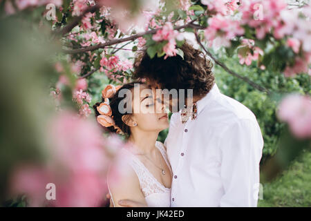 Medio Orientale giovane baciare sotto alberi fioriti Foto Stock