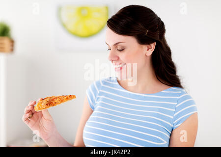 Donna felice di mangiare la pizza a casa cucina Foto Stock