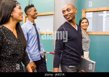 La gente camminare e sorridente in ambienti interni Foto Stock