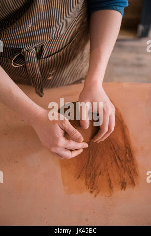 Le mani della donna caucasica laminazione di argilla in ceramica Foto Stock