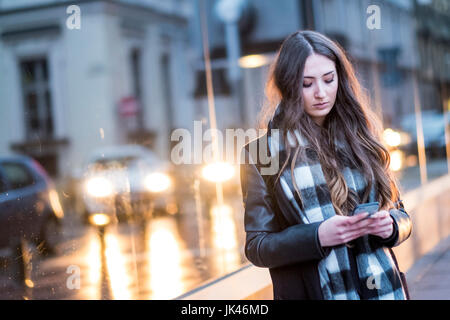 Grave donna caucasica sms sul cellulare all'aperto Foto Stock