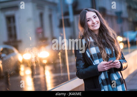 Sorridente donna caucasica sms sul cellulare all'aperto Foto Stock