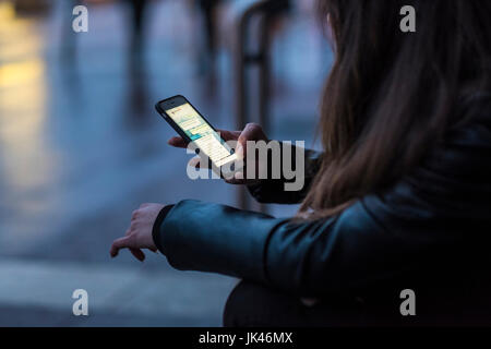 La donna caucasica sms sul cellulare all'aperto Foto Stock