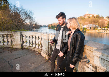 Coppia caucasica sms sul cellulare vicino al fiume Foto Stock