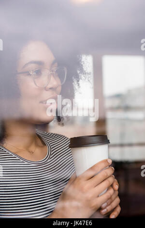 Malinconici americano africano donna di bere il caffè dietro la finestra Foto Stock