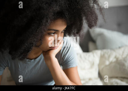 Infelice americano africano donna seduta nel letto Foto Stock