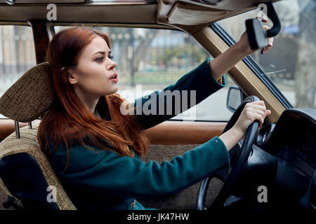 Caucasian donna alla guida di auto regolazione specchietto Foto Stock