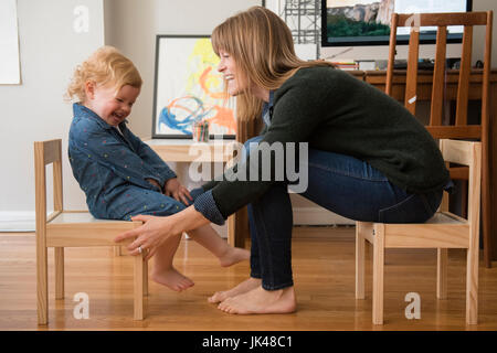 Caucasian madre e figlia seduti su piccole sedie in home office Foto Stock