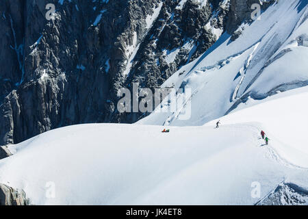 Gli alpinisti salire una lunga salita congelati circondato da ghiaccio e neve con un ghiacciaio in background sul Mont Blanc Foto Stock