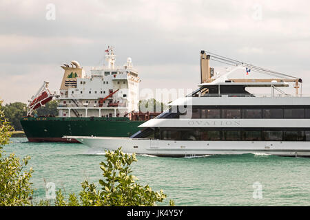 Detroit, Michigan - Ovation, un lussuoso yacht charter, passa il Bluewing, un grande lago carichi alla rinfusa nave, sul Fiume Detroit. Foto Stock