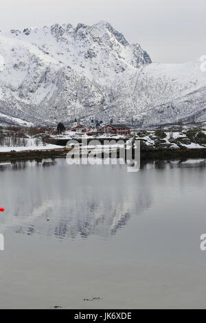 Cottage di rosso e sjohus-seahouse. Cappella bianca-penisola Sildpollnes visto da S.shore Sildpolltjonna bay. Kroktindan-Litlkorsnestinden mts.background Foto Stock