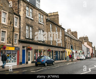 Vista lungo la strada del mercato, Haddington, East Lothian, Scozia, Regno Unito, sul bagnato estate pomeriggio con Kelsey's Bookshop e fiori colorati in cestelli Foto Stock