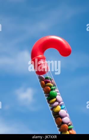 Plastica trasparente candy cane con maniglia rossa riempita di cioccolato colorato di fagioli dolci. Foto Stock