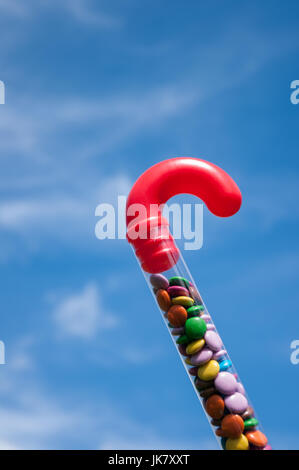 Plastica trasparente candy cane con maniglia rossa riempita di cioccolato colorato di fagioli dolci. Foto Stock