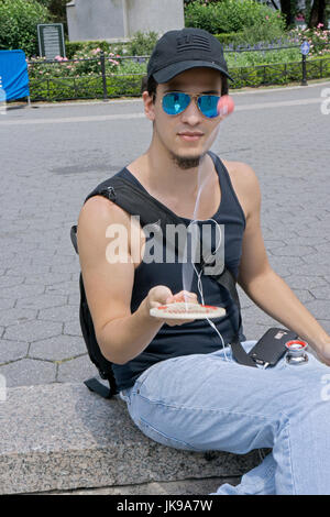 Un giovane uomo in Union Square Park a giocare il vecchio gioco semplice, paddle ball. Foto Stock