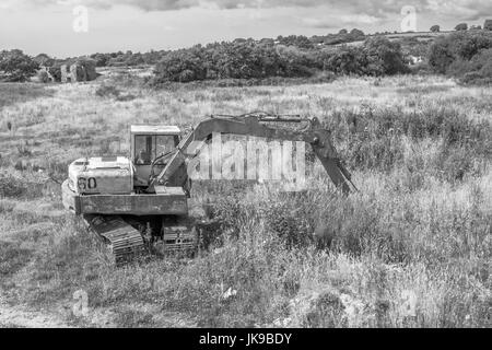 Abbandonato digger visto in un campo irregolare. Foto Stock