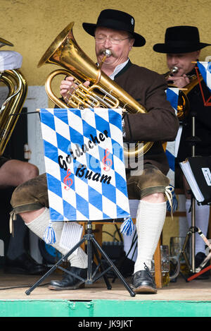 Musicista in costume bavarese la riproduzione della tuba in una banda di ottoni seduto su una sedia Foto Stock
