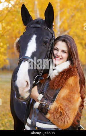 Ritratto di una bella donna giovane con un nero equitazione giorni di autunno Foto Stock