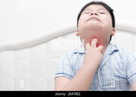 Asian boy obesi graffiare il prurito con mano sul letto, concetto con la sanità e la medicina Foto Stock