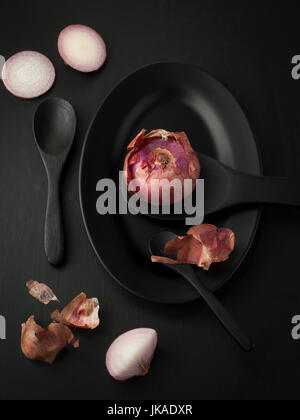 Rosso porpora o cipolla condimento mixer food erba o cibo sano per la cura della pelle nero sul cucchiaio piatto e vasellame nero su sfondo di legno Foto Stock