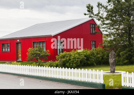 Coloratissima casa rossa con un recinto di picchetti bianchi in Islanda Foto Stock