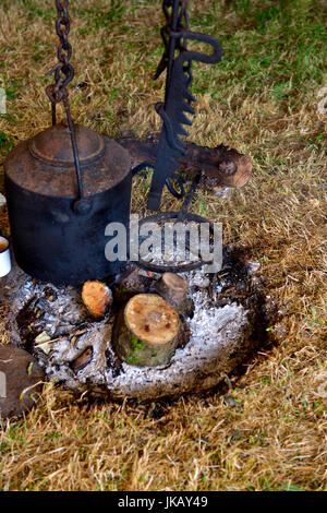 Ghisa nera pentola appesa sopra la combustione del legno del fuoco Foto Stock