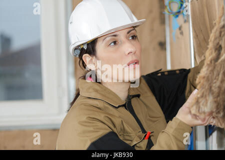 Lavoratore di sesso femminile che ponendo il foglio di polistirolo isolamento a parete Foto Stock
