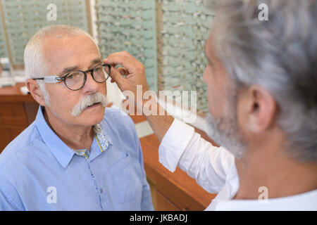 Senior uomo cercando montature per occhiali a ottico Foto Stock