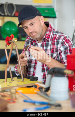 Plumber avvitando il dado del tubo con una chiave in corrispondenza del workshop Foto Stock