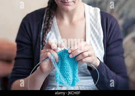 Un buio dai capelli donna con una spiralina in un abito a strisce con una profonda scollatura a maglia una sciarpa di lana blu filettature a casa Foto Stock