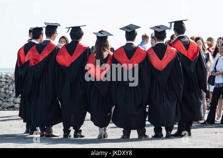 Un gruppo di nuovi laureati aventi le loro fotografie scattate da membri della famiglia, all'esterno, dopo la cerimonia di laurea. Foto Stock