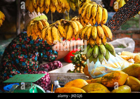 Appendere le banane per la vendita nel mercato locale in Cambogia. Qui tutto è organico e proveniva direttamente dai contadini Foto Stock