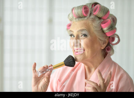 Close up ritratto di donna senior in accappatoio di applicare il make up Foto Stock