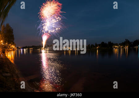 Fuochi d'artificio sul fiume Ticino in una serata estiva con il paesaggio sullo sfondo, finale della mostra Foto Stock