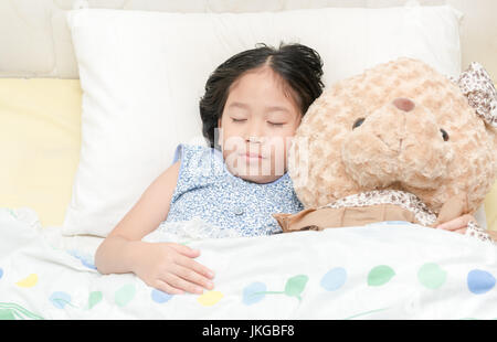 Adorabile bambina dormire nel letto con il suo orsacchiotto Foto Stock