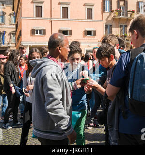 Square ritratto di una strada peddler mostrando la sua estendibili plastilina giocattolo per un gruppo di bambini. Foto Stock