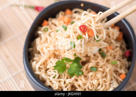 Chiuso fino tagliatelle istante con verdure su chopstick, cibo spazzatura o fast food concept. Foto Stock