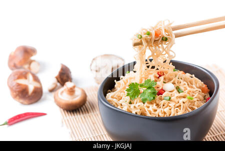 Chiuso fino tagliatelle istante con verdure su chopstick isolati su sfondo bianco, cibo spazzatura o fast food concept. Foto Stock