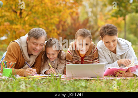 Felice padre, madre e figli a fare i compiti in posizione di parcheggio Foto Stock