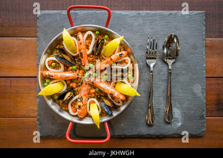 La paella con frutti di mare e verdure zafferano servito nel tradizionale pan vista dall'alto. Foto Stock