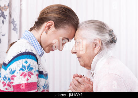 Aiutando le mani, la cura per gli anziani concetto Senior e il caregiver tenendo le mani a casa Foto Stock